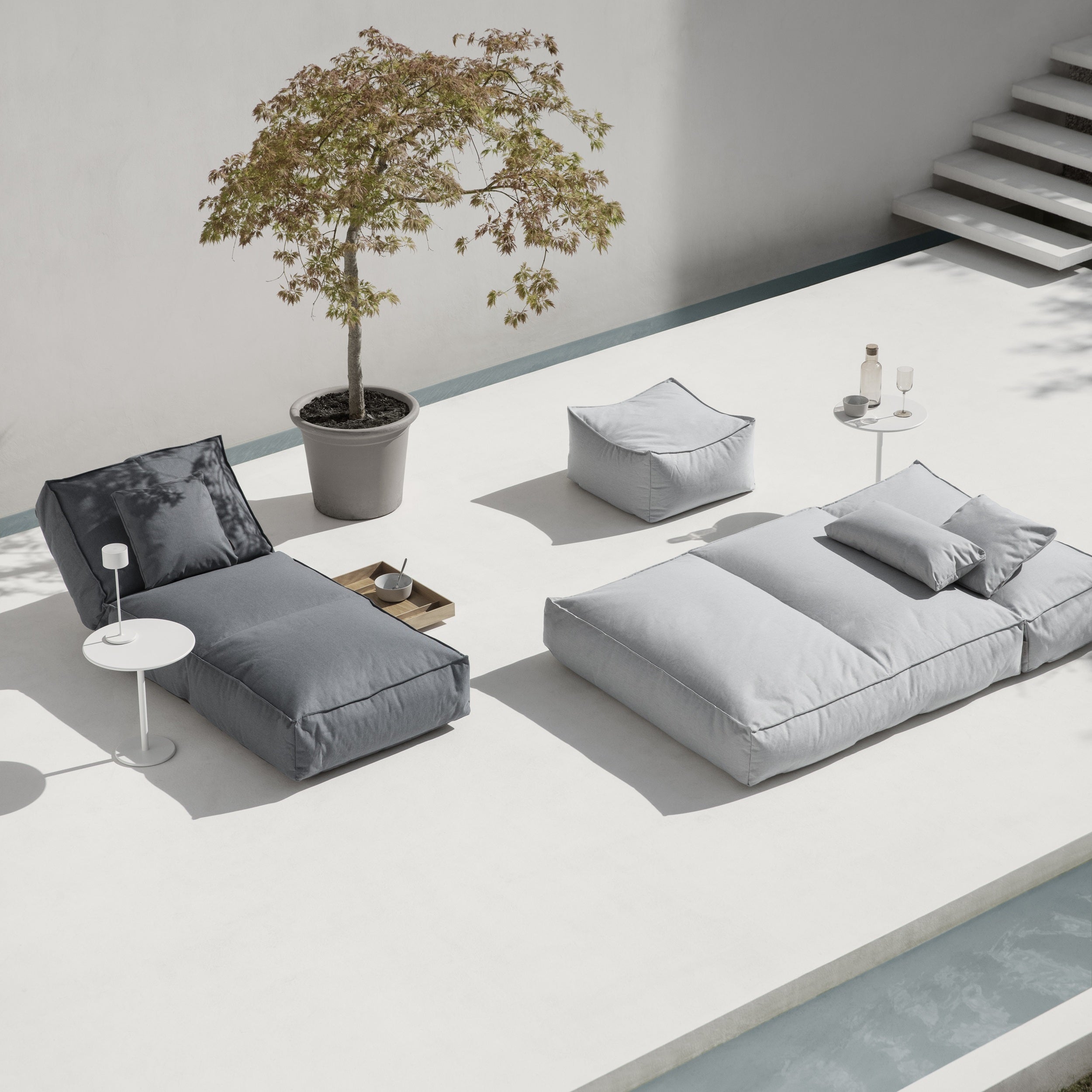 Modern outdoor furniture set with gray cushions on a white patio.