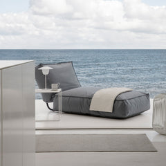 Gray lounge chair with a blanket on a modern patio with ocean view