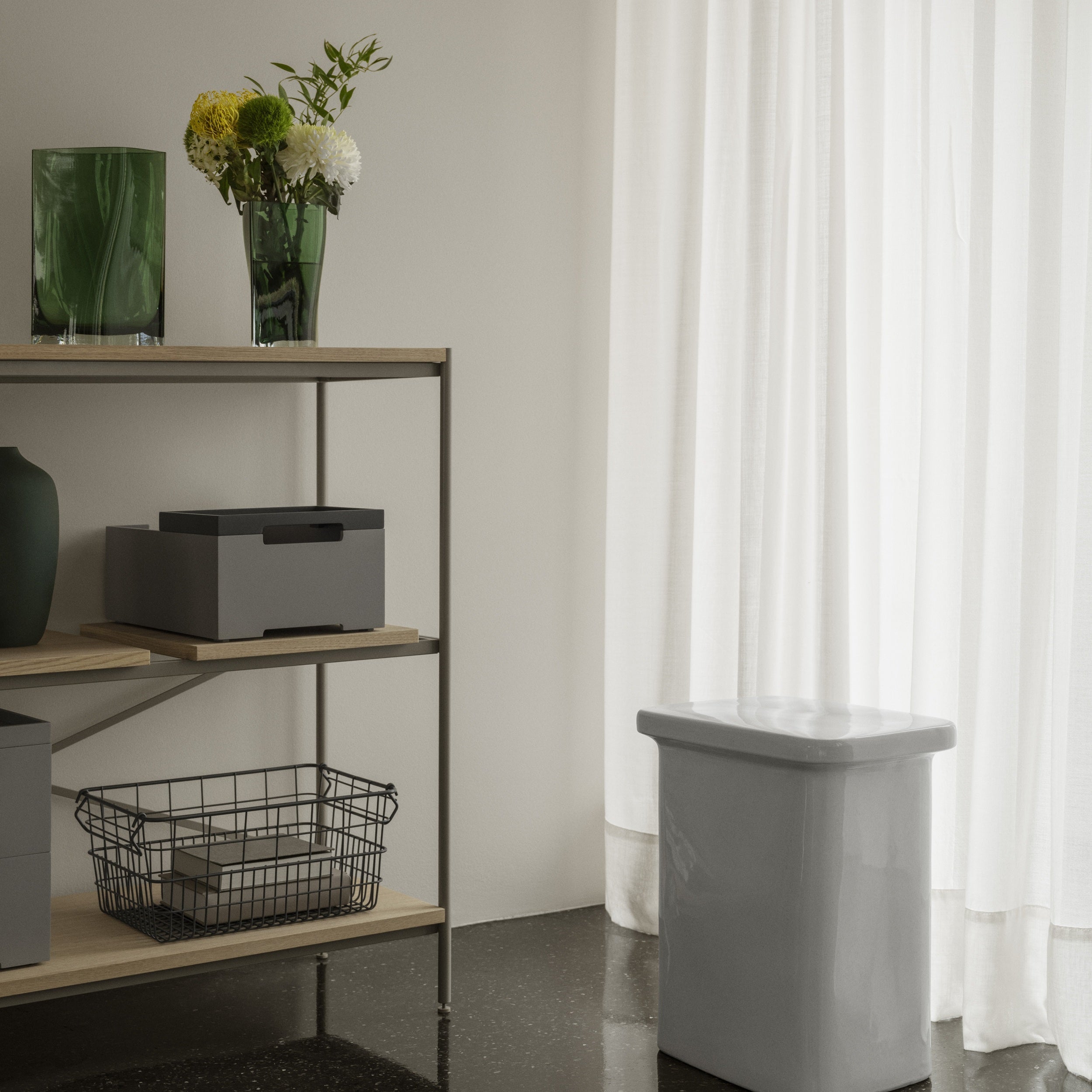 Shelving unit with decorative items next to a curtain-draped window