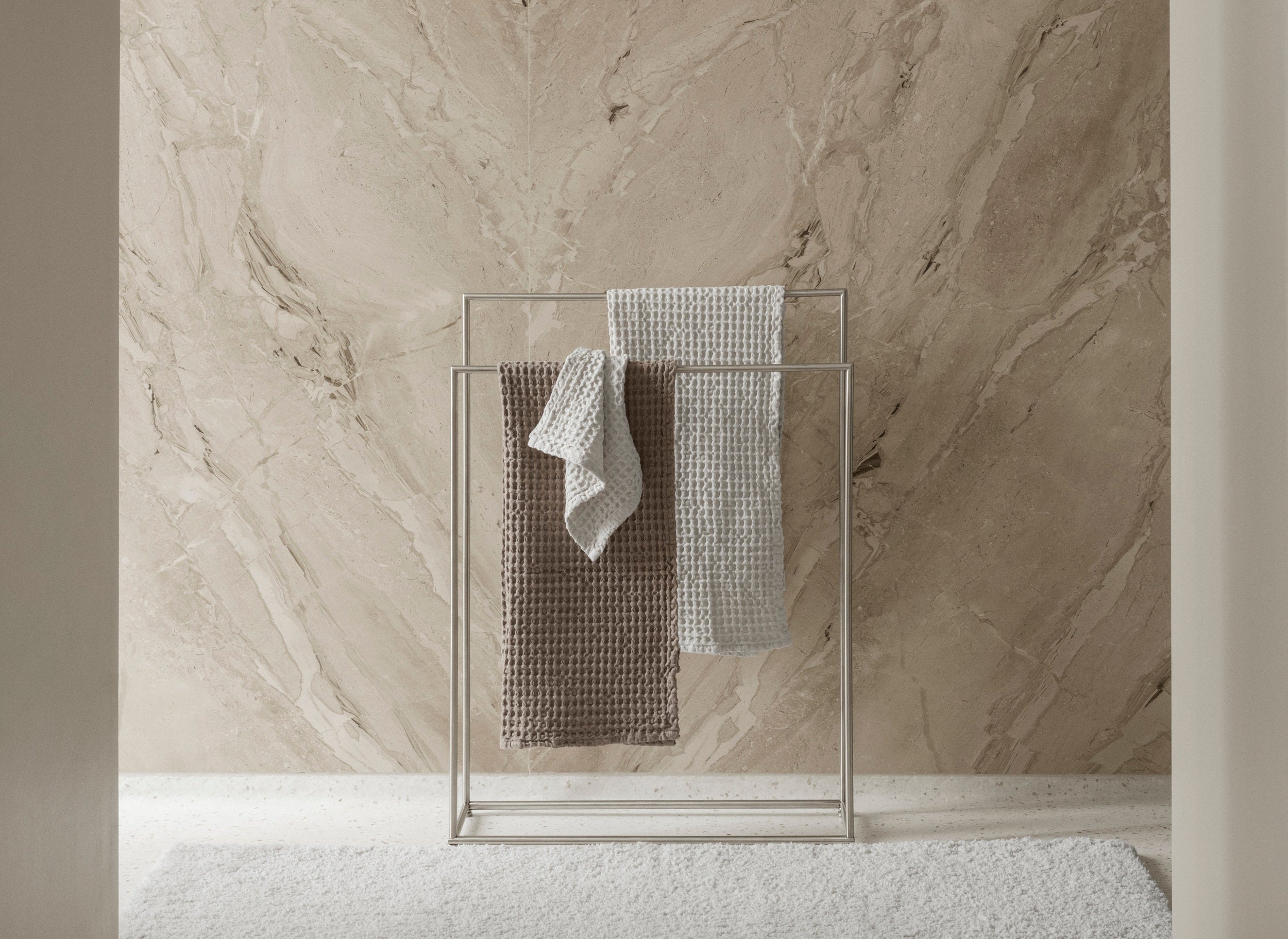 Towel rack with towels against a marble wall