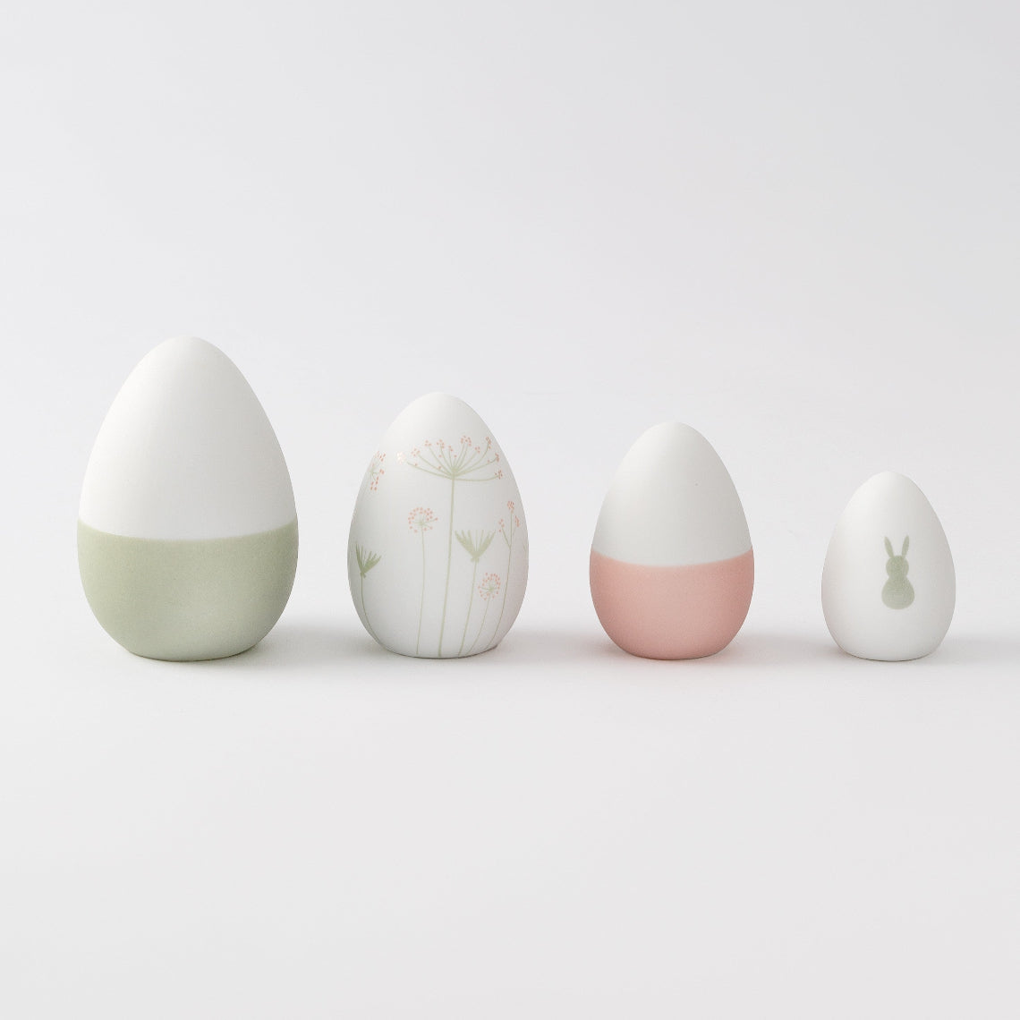 R17462 Four porcelain Easter decorative eggs with different designs on a light gray background