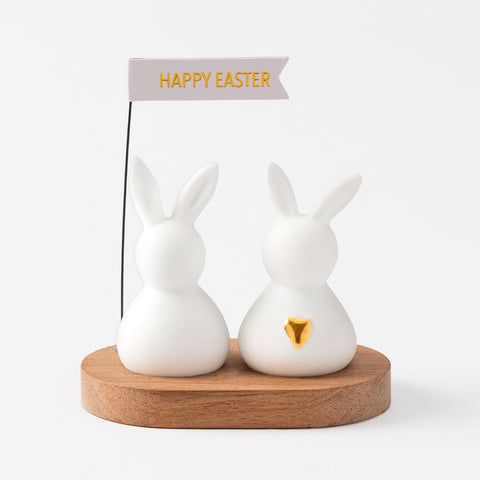 R17463 Two porcelain bunnies on an acacia wood tray holding a happy easter sign.