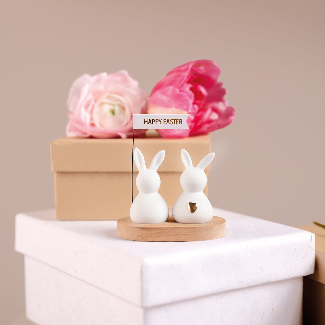 Easter Bunny Greetings Porcelain Bunny Decoration sitting atop a white box with pink flowers behind it.