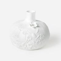 Porcelain Stories White porcelain vase with floral patterns on a white background.