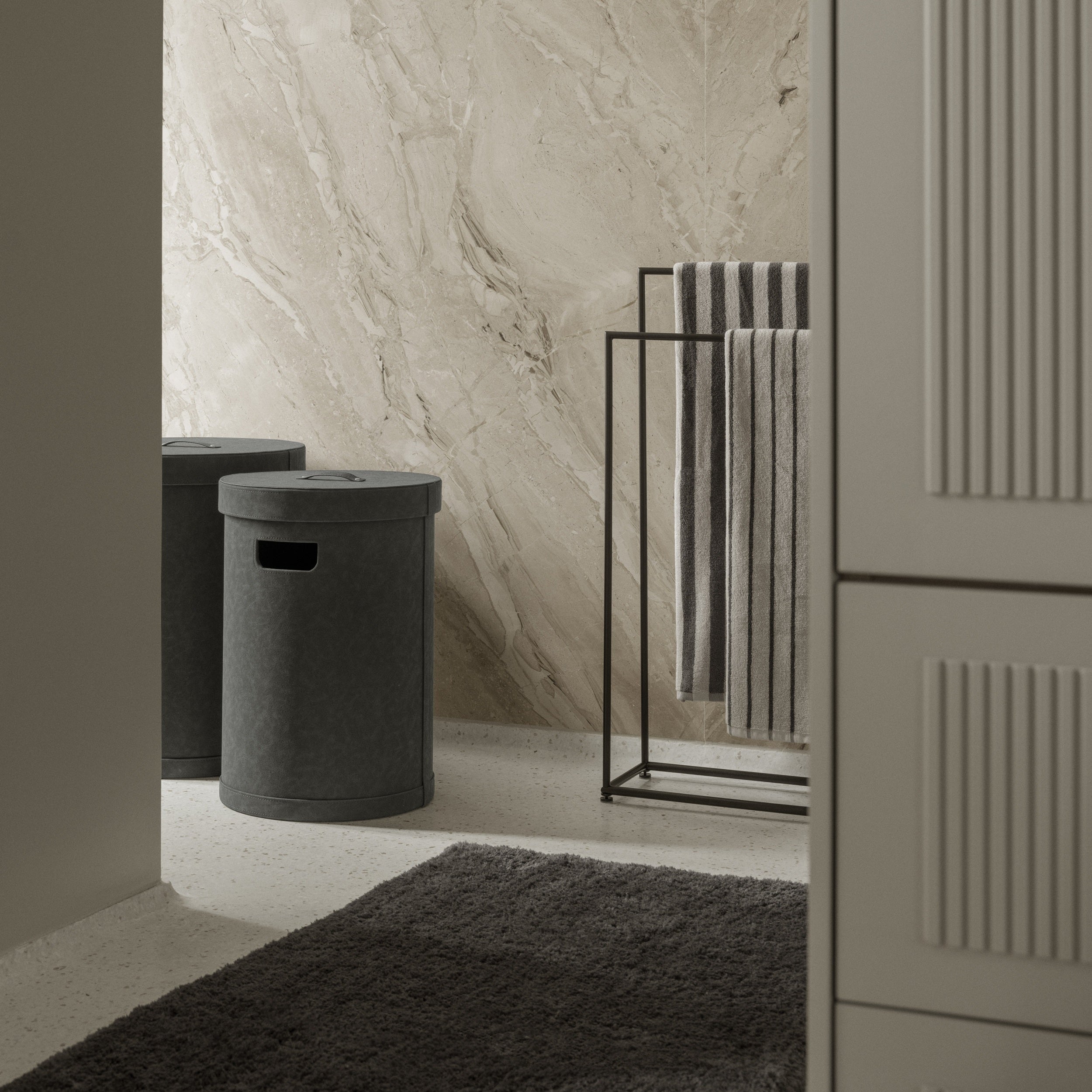 Bathroom interior with a towel rack, storage bin, and textured wall.
