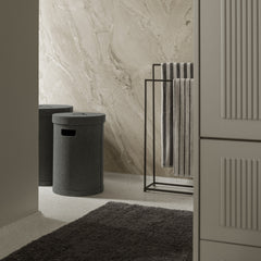 Bathroom interior with a towel rack, storage bin, and textured wall.